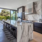 Stylish kitchen featuring marble countertops, stainless steel appliances, and a large island with bar stools in a contemporary setting